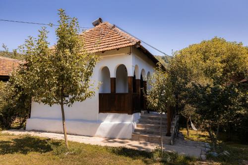 uma pequena casa branca com uma porta e árvores em Sentina kuća em Vrtovac