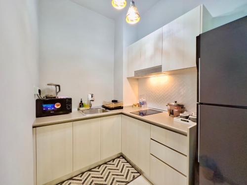 a kitchen with white cabinets and a black refrigerator at #9 Jesselton Quay City Pads Seaview by Zeluxo in Kota Kinabalu