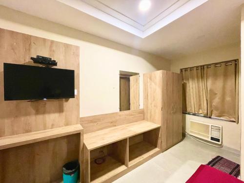 Hotel Janaki Pride, Puri fully-air-conditioned-hotel spacious-room with-lift-and-parking-facility في بوري: غرفة معيشة مع تلفزيون بشاشة مسطحة على جدار