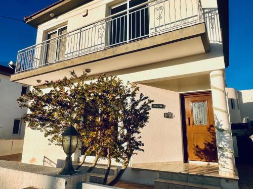 un edificio con balcón y un árbol delante de él en Athena Villa, en Lárnaca