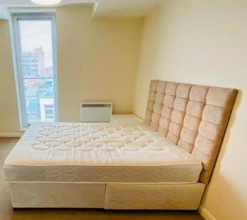 Cette chambre comprend un grand lit et une grande fenêtre. dans l'établissement Centrally Located 3 Bed Apartment, à Cardiff