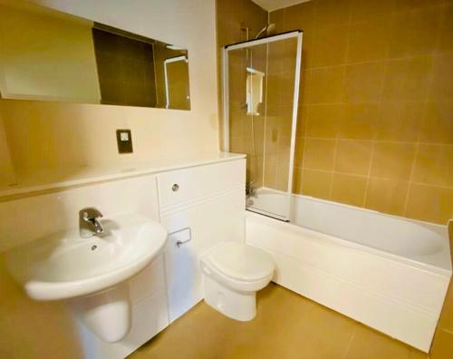 a bathroom with a sink and a toilet and a tub at Centrally Located 3 Bed Apartment in Cardiff