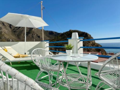 een tafel en stoelen en een parasol en de oceaan bij Villa Portús in Portús