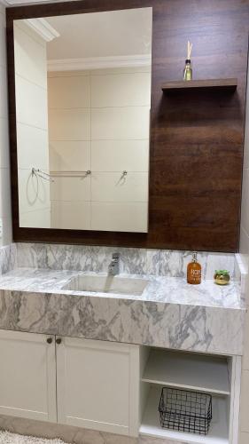 a bathroom with a sink and a mirror at Residencial Don Alfredo-Luxo Gramado 2 km do centro locação de temporada in Gramado