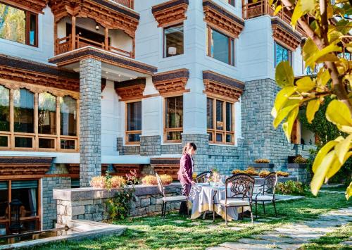 a woman standing at a table in front of a building at The Indus Valley in Leh