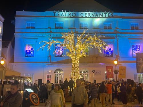 un grupo de personas de pie fuera de un edificio con un árbol con luces en Fantastic Penthouse Malaga Center, en Málaga