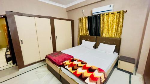 a bedroom with a bed with white sheets and yellow curtains at Prince Castle-4BHK Apartment,Guesthouse in Hyderabad