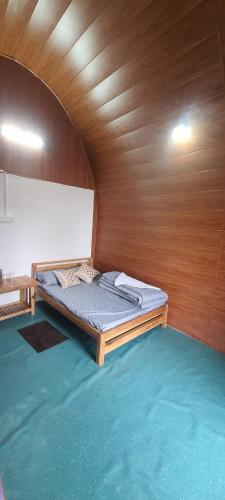 a bed in a room with a wooden wall at New bloom homestay in Mangpu