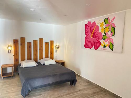een slaapkamer met een bed en een schilderij aan de muur bij La Maison Calebasse in Saint-François