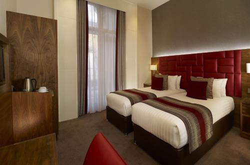 Habitación de hotel con 2 camas y cabecero rojo en Norfolk Towers Paddington, en Londres