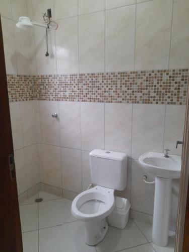 a bathroom with a toilet and a sink at Casa de praia com piscina in Itanhaém