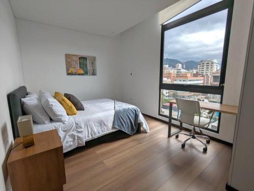 a bedroom with a bed and a desk and a large window at Stylish 2 bedroom near Parque 93. FREE Parking. in Bogotá