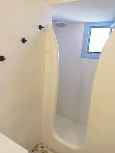 eine weiße Badewanne mit Fenster in einem Badezimmer in der Unterkunft Anemousa Hotel in Folegandros Chora