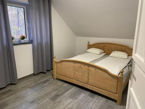 sypialnia z drewnianym łóżkiem i oknem w obiekcie Yacht Club Apartamenty w mieście Radzyń