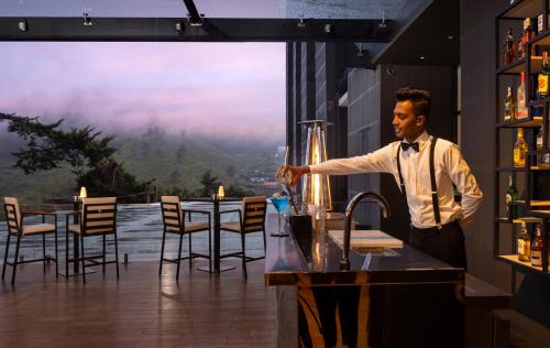 a man standing at a bar with a glass of wine at The Golden Ridge Hotel in Nuwara Eliya