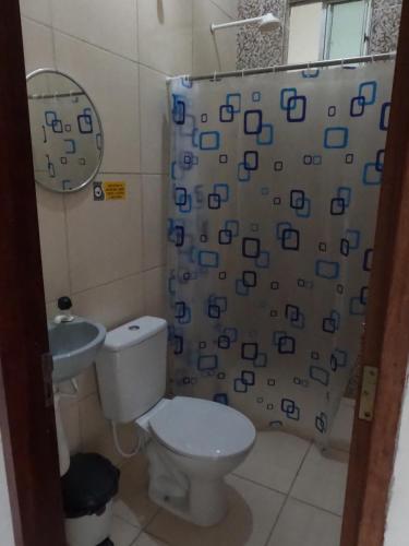 a bathroom with a toilet and a shower curtain at Flat Japaratinga Beach in Japaratinga