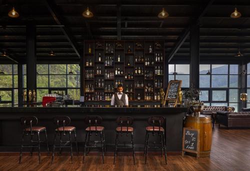 a woman standing behind a bar with stools at The Golden Ridge Hotel in Nuwara Eliya