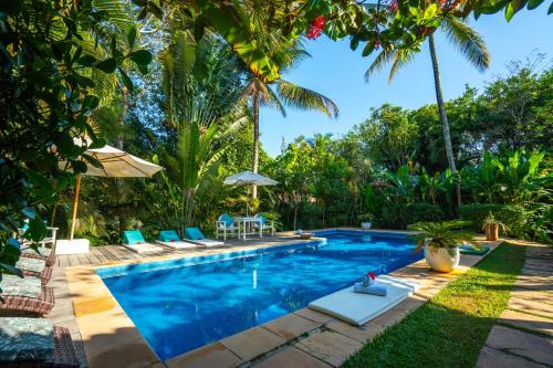 a pool with chairs and umbrellas in a yard at Pousada Jardim Das Margaridas in Trancoso