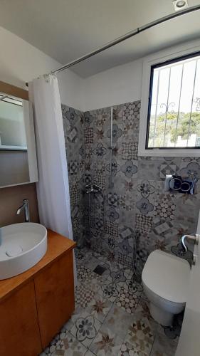 a bathroom with a sink and a toilet and a window at Beachfront Oleanders House in Skala in Skala Kefalonias