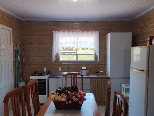 a kitchen with a table and a white refrigerator at CASA DE PRAIA ILHA in Araranguá