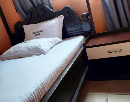 uma cama com uma cabeceira de madeira ao lado de uma cómoda em California Lodge em Bagamoyo