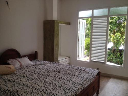 a bedroom with a bed and a large window at MIST in Ambalangoda