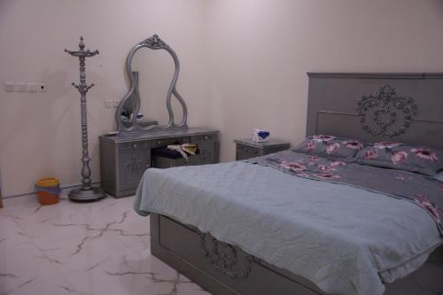 a bedroom with a bed and a dresser and a cross on the wall at شقق ريام جيزان للعوائل in Jazan