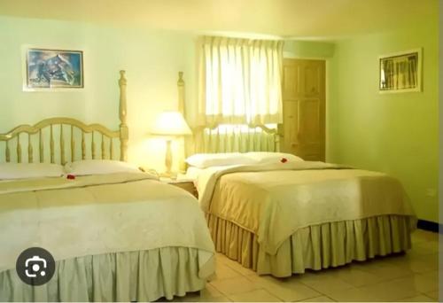 a hotel room with two beds and a window at Big Apple Hotel in Montego Bay