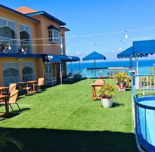 a building with a yard with tables and umbrellas at Big Apple Hotel in Montego Bay