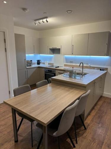 cocina con mesa de madera con sillas y fregadero en Spacious 2 Bedroom Flat With Balcony, en Barking