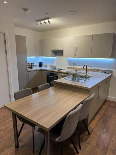a kitchen with a wooden table with chairs and a sink at Spacious 2 Bedroom Flat With Balcony in Barking