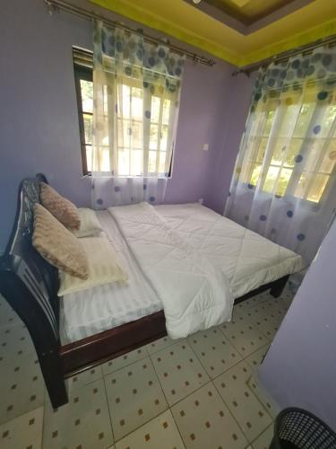 1 dormitorio con 1 cama con sábanas blancas y ventana en Christa's Haven, en Siaya