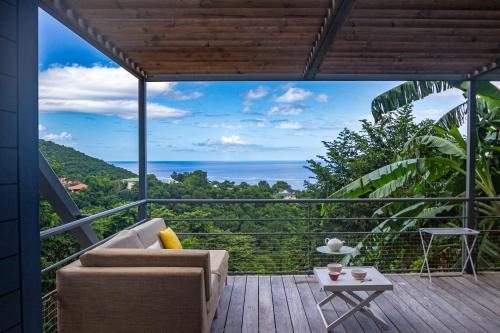 a balcony with a couch and a view of the ocean at Les Cabanes Perchées in Bouillante