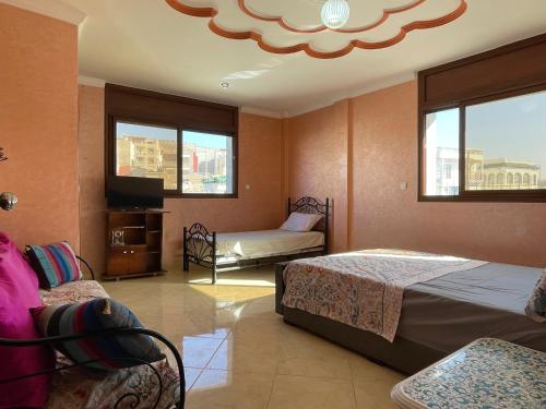 una camera con due letti, una TV e finestre di Villa de l'ermitage a Imsouane