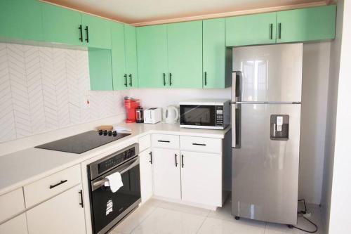 cocina con armarios verdes y nevera de acero inoxidable en Irie Vibes Ocean View en Negril