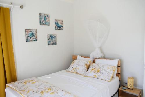 a white bed with pillows and pictures on the wall at Irie Vibes Ocean View in Negril
