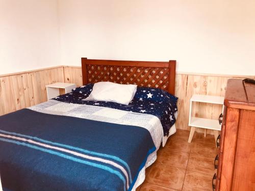 a bedroom with a bed with a blue blanket and two chairs at Tifrys in La Serena