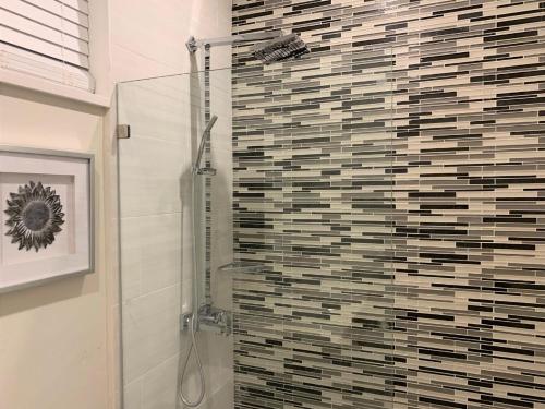 a bathroom with a shower with a tile wall at Jamaica Bookings in Montego Bay