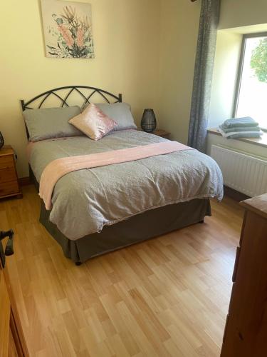 un letto in una camera da letto con pavimento in legno di Castlegregory-Seaside 2 Bedroomed Cottage a Castlegregory