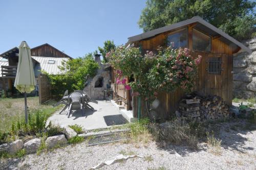 un jardin avec un banc et un bâtiment fleuri dans l'établissement LE LOVE CHALET DES ALPES, à Guillestre