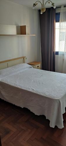 - une chambre avec un grand lit et un couvre-lit blanc dans l'établissement Ciudad de Sada, à Sada