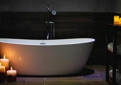 a bath tub in a bathroom with two candles at Parra del Valle Hotel Boutique in Valle de Guadalupe