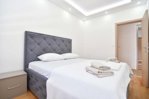 a bedroom with a bed with white sheets and towels at KAAN APARTMENT in Budva