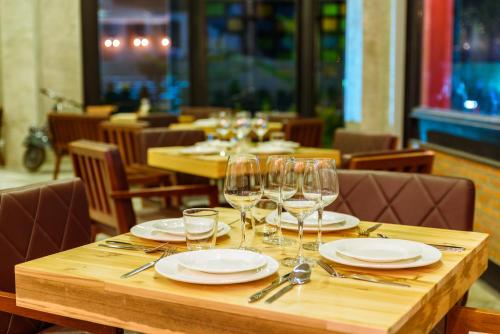a wooden table with plates and wine glasses on it at S Park Design Hotel in Vientiane