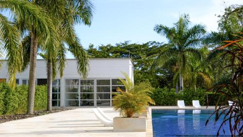 a house with a swimming pool and palm trees at Hotel Morúa in Yopal