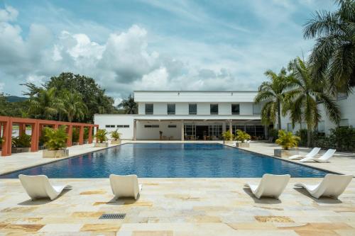 a swimming pool with lounge chairs in front of a building at Hotel Morúa in Yopal