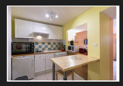 une cuisine avec des armoires blanches et une table en bois dans l'établissement Asphodèle, T2 bis, extérieur, wifi, parking, 6 personnes, à Cauterets