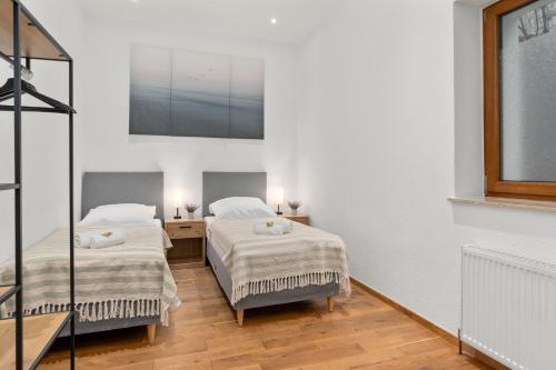 Cet hébergement comprend 2 lits dans une chambre dotée de murs blancs et de parquet. dans l'établissement homey Apartments Park Suite, à Bremerhaven