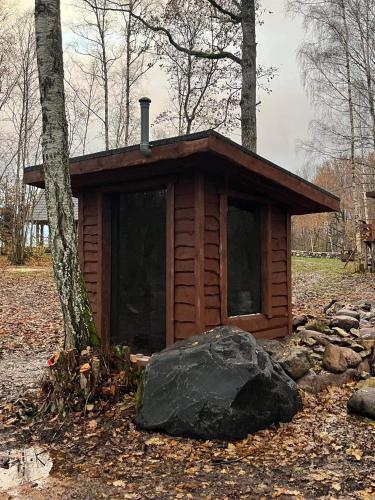 a small cabin in the woods with a rock at Lepikumäe Holiday Home with Sauna and Hot tub for up to 18 persons in Reina