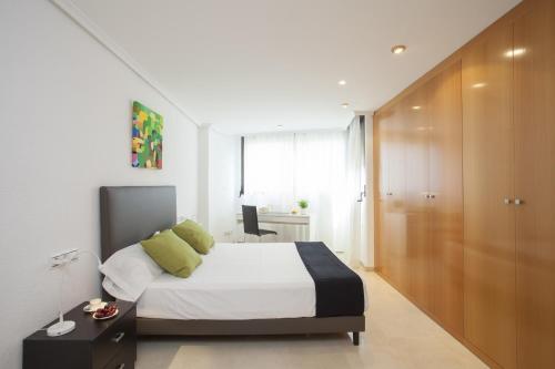 バレンシアにあるApartments Serrería IIのベッドルーム1室(白いシーツと緑の枕が備わるベッド1台付)